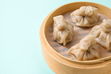Bamboo steamer with tasty dumplings on color background, closeup