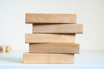 A pile of five wooden blocks on the soft white background. - Powered by Adobe