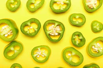 Slices of green jalapeno peppers on color background