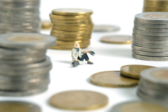 Miniature people toy figure photography. Bankruptcy concepts. A beggar man with no money seat in the middle of coin stack money. Isolated on white background. Image photo