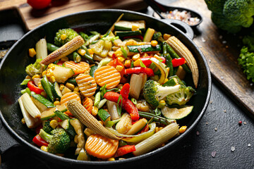 Frying pan with different vegetables on dark background, closeup