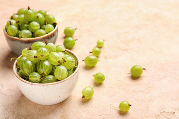 Bowls with fresh ripe gooseberry on color background