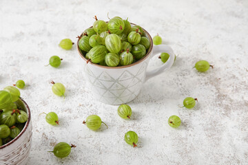 Cup with fresh ripe gooseberry on grunge background
