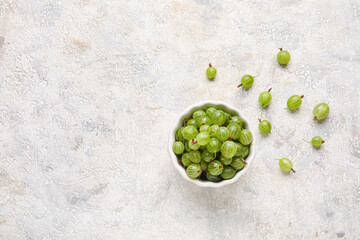 Bowl with fresh ripe gooseberry on grunge background