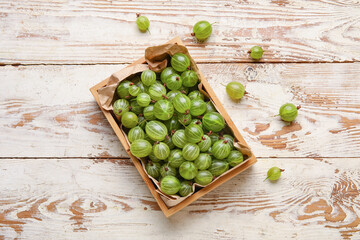 Box with fresh ripe gooseberry on wooden background