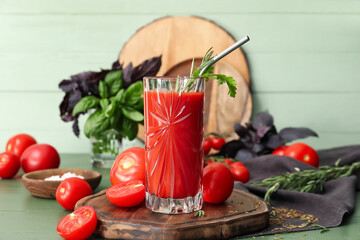 Glass of tasty tomato juice on color wooden background