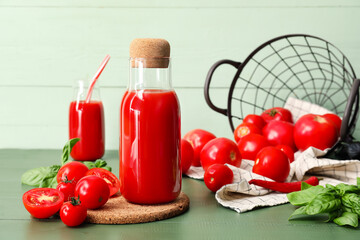 Bottle of tasty tomato juice on color wooden background