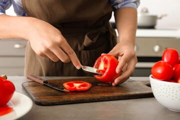 Woman preparing stuffed tomatoes at table in kitchen, closeup