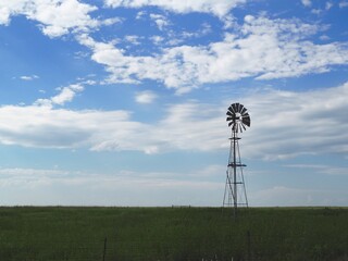 Old-fashioned windmill pumping water in the Flint Hills of Kansas.  - obrazy, fototapety, plakaty