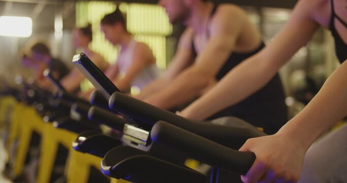 Group of athletic young people stationary bicycle doing spinning at gym . A group of young women and men train on sports training equipment in a fitness gym . Healthy Lifestyle and Sport Concepts