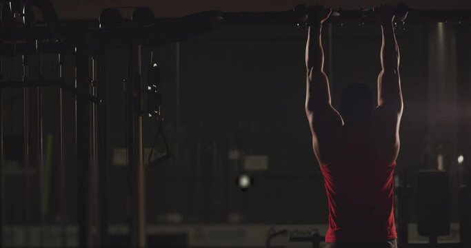 4k Healthy athlete man training pull ups exercise enjoying intense fitness workout . Back view of sportsman doing pull ups in gym . Shot on RED DRAGON Cinema Camera in Slow Motion
