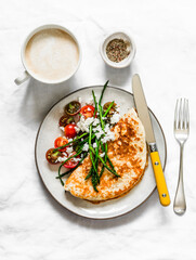 Oatmeal crepes without flour with asparagus, feta, cherry tomatoes and cappuccino - delicious diet breakfast on a dark background, top view