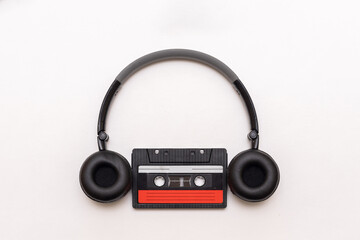 On-ear black headphones and old analog magnetic cassette isolated on white background, close-up