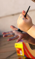 Mãos de uma criança brincando com pincel de tinta