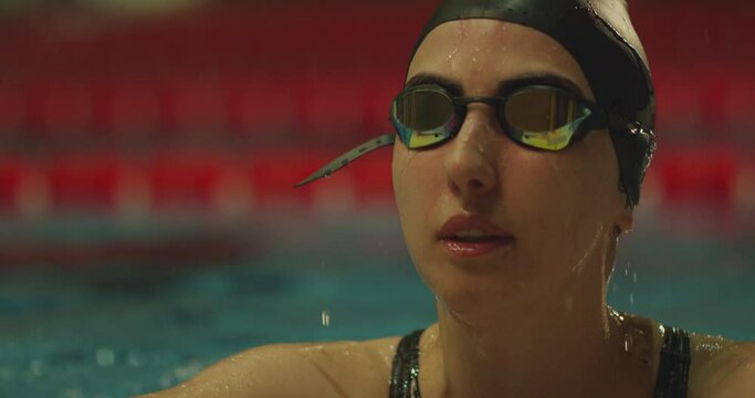 Portrait of professional female swimmer in goggles on swimming pool . Exit from swimming pool . Woman swimmer dive in water pool . Girl swimming underwater in the large pool . Close up , slow motion .