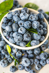 Freshly picked blueberries in a  bowl. Juicy and fresh berries with green leaves on a rustic table.  Healthy food and nutrition concept