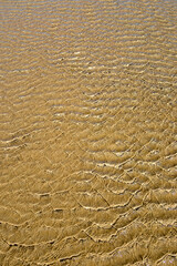 Sand texture, thin layer of water left on the sand when the tide goes out