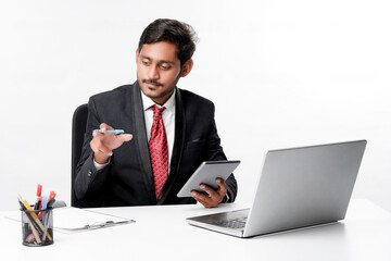 Young indian man in suit and using tablet and laptop at office