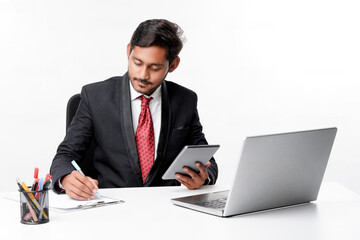 Young indian man in suit and using tablet and laptop at office