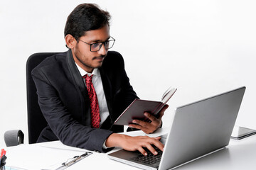 Young indian businessman cheaking or reading dairy at office.