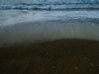 Wave on the sandy beach at twilight.