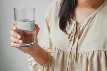 Young woman holding drinking water glass in her hand. Health care concept.Room temperature water.