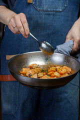 A chef mixes the shrimp in a frying pan