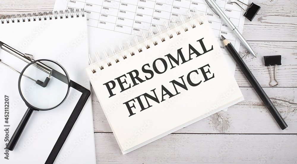 Aufkleber notepad with text personal finance with a pen,office tools and graphs on the desktop.
