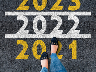 happy new year 2022. lets start 2022. woman legs in shoes walks on asphalt road next to number 2022...