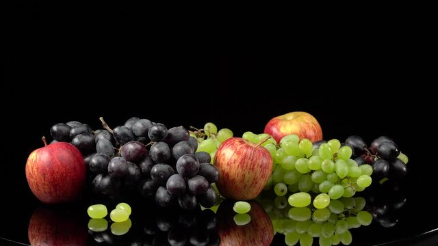 Still life with grapes and apples on a black background.
