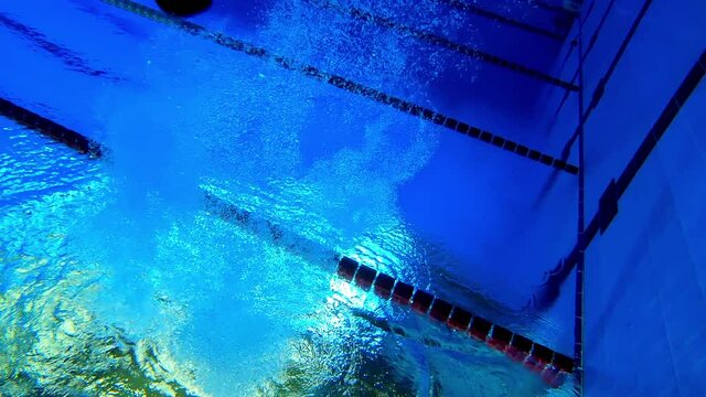 Under water view of professional female swimmer . Underwater footage of woman jumping into water . Swimmer jumping in big swimming Woman swimmer dive in water pool .  Slow Motion .