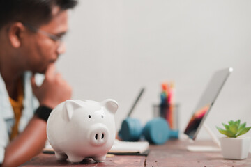 Saving money for education , Young men with a piggy bank put on an income planning book to spend on education.

