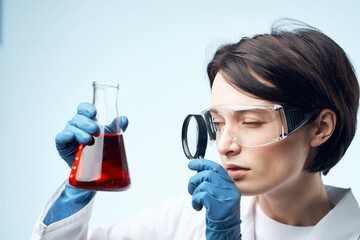 female laboratory assistant looks through a magnifying glass at a biochemical research process