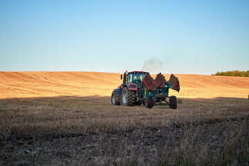 Obraz premium Agricultural work. Tractor with a plow on a summer field during the day