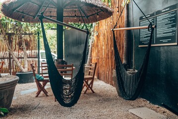 Hanging swing chair with empty table and chair at outdoor beach cafe. Tulum, Mexico.