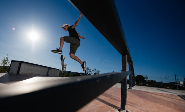 View of a young man through a railing jumping on a skate park.