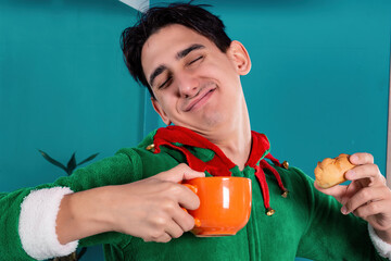 A funny guy in elf pajamas drinks hot coffee in the morning in the bathroom. New Years Eve.