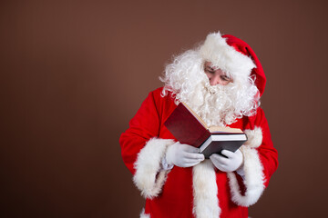 Funny Santa Claus reads books. Brown background.