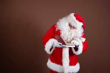 Funny Santa Claus reads books. Brown background.