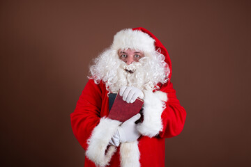 Funny Santa Claus reads books. Brown background.