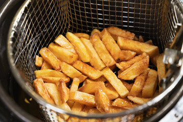 a basket of potatoes is taken out of the deep fryer. cooking french fries 
