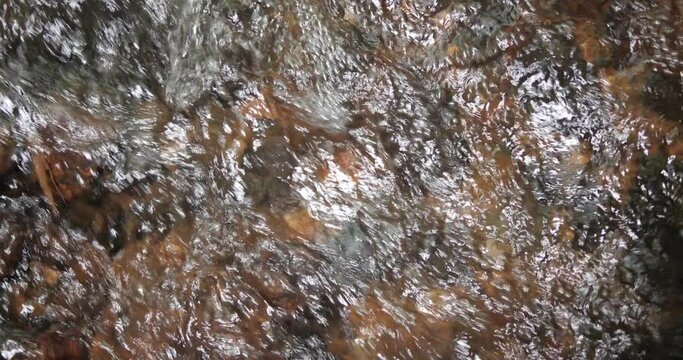 Top view of clear mountain river water with rocks and splashes. Background of fresh waterfall stream in forest.