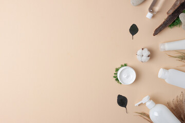 Cosmetic skin care products with flowers and wood on pastel beige background. Flat lay, copy space