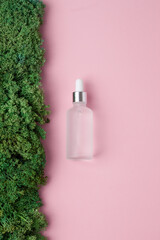 Cosmetic bottle with moss natural background on pink. Flat lay