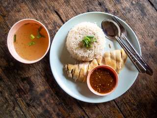Chicken rice, Thai food, high angle There is rice and boiled chicken on a high angle white plate on a wooden table. There is space for text.