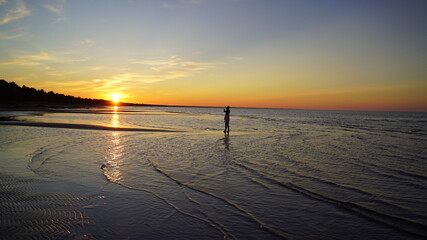 Fototapeta na wymiar silhouette of a woman at sunset on the sea coast