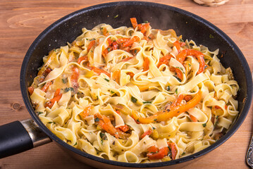 Fettuccine pasta with creamy bell pepper sauce in a pan, close-up