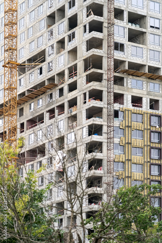 Poster view of frame part of metallic crane machinery attachment at windows of new residential building con
