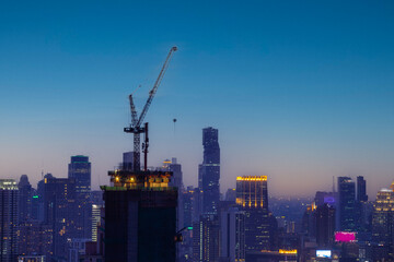 Fototapeta na wymiar silhouete photo of Hight rising crane working on building with sunset twilight sky background
