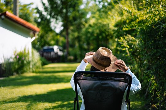 Man wearing straw hat relaxing in chair in the garden